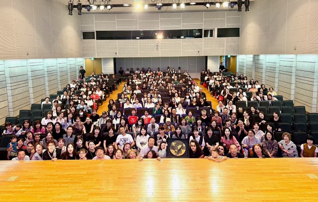 イベント会場の集合写真。ステージ前のメンバーと客席の参加者